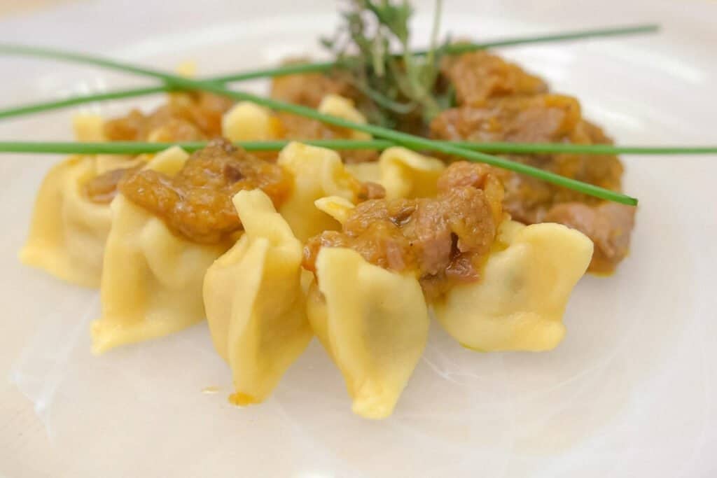 Idrija Žlikrofi, potato filled pasta with cracknels, butter, and garnish