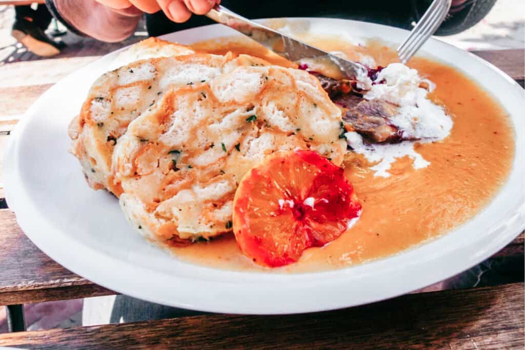 svíčková dish from the Czech Republic - bread on a plate with soup, slice of orange, and meat